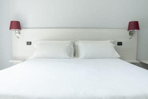 uma cama branca com 2 almofadas brancas e 2 candeeiros em Hotel Pone em Sesto San Giovanni