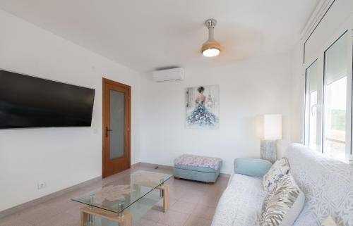 a living room with a white couch and a flat screen tv at Unter den Linden in Comarruga