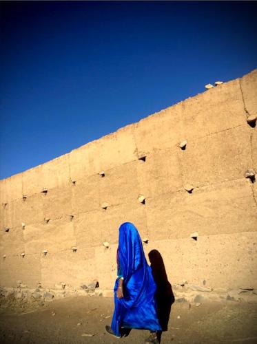 a woman in a blue hijab standing in front of a brick wall at Maison d'hôte ''J'' in Agdz