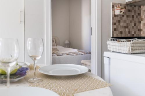 a white room with a table with a plate and wine glasses at 2 Bedroom house and Garden Lounge in Sintra