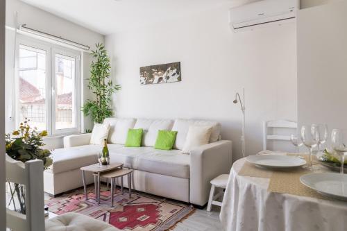 a white living room with a white couch and green pillows at 2 Bedroom house and Garden Lounge in Sintra