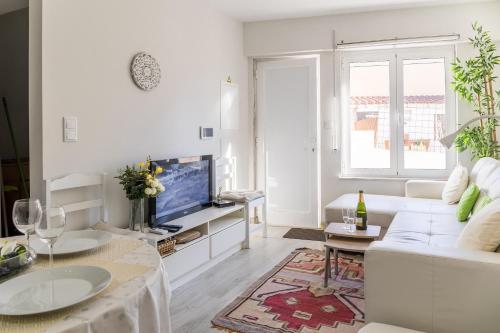 a white living room with a white couch and a tv at 2 Bedroom house and Garden Lounge in Sintra