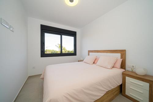 ein weißes Schlafzimmer mit einem großen Bett mit rosa Kissen in der Unterkunft Lo Romero in Pilar de la Horadada