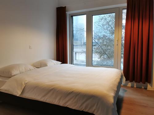 - une chambre avec un grand lit et une grande fenêtre dans l'établissement Ooostel2be Brussel, à Bruxelles