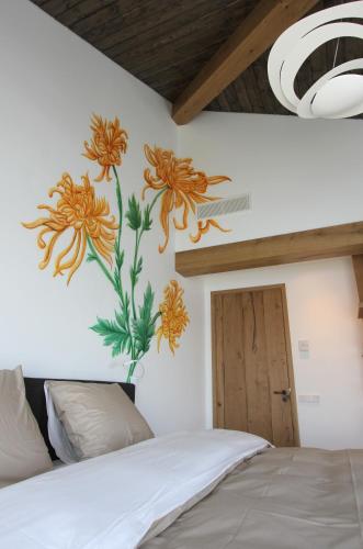 a bedroom with a painting of flowers on the wall at als het golft in Roelofarendsveen