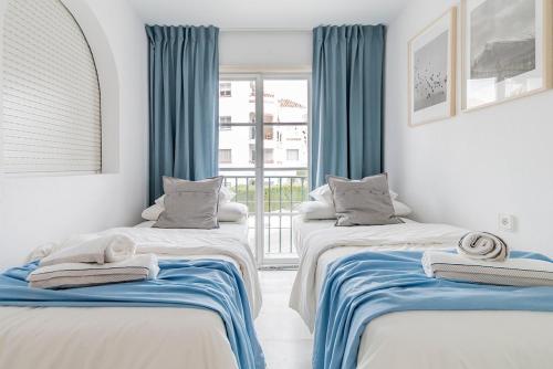 2 łóżka w pokoju z niebieskimi zasłonami w obiekcie Lovely 2 Bedroom Apartment w/ large garden + pools w mieście Benalmádena
