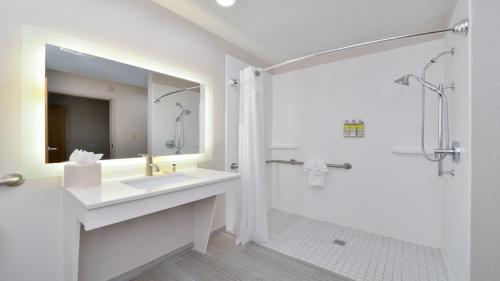 La salle de bains blanche est pourvue d'un lavabo et d'une douche. dans l'établissement Holiday Inn Express Hotel & Suites La Place, an IHG Hotel, à La Place