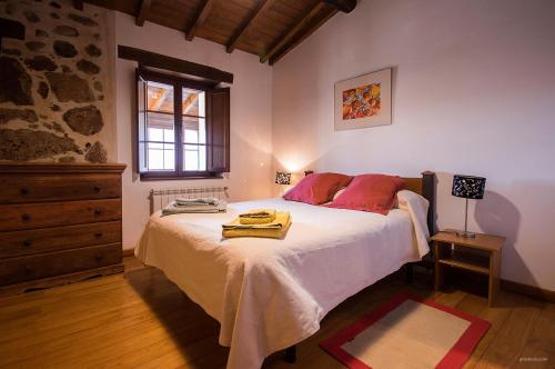 a bedroom with a bed with red pillows and a window at O Canto da Terra in Pantón