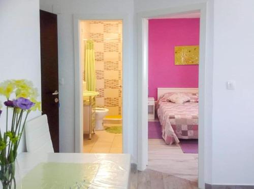 a bedroom with pink walls and a bed with a table at Apartments Leon in Orebić