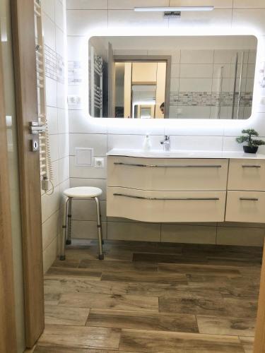 a bathroom with a sink and a mirror and a stool at Part Royal Apartments in Keszthely