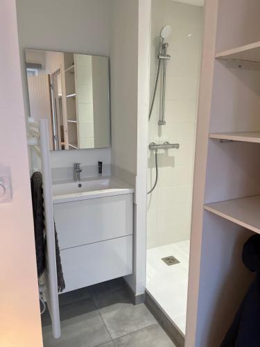 une salle de bain blanche avec un lavabo et une douche dans l'établissement Lamballe plein centre, superbe appartement 1er étage, à Lamballe