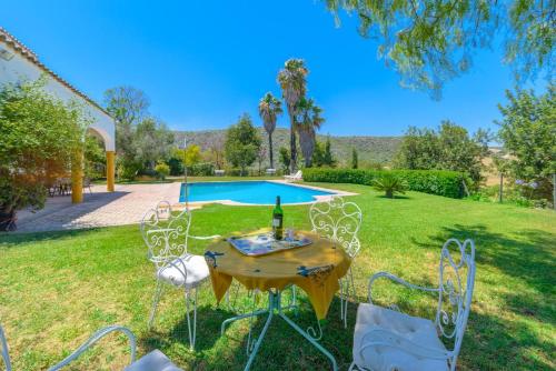 una mesa con una botella de vino en un patio en Alterhome Private Villa Cortijo Sierra y Lago, en Arcos de la Frontera