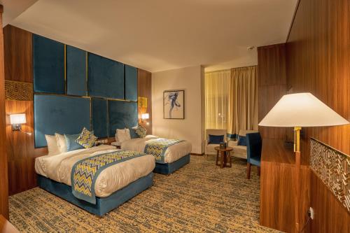 a hotel room with two beds and a lamp at Le Park Concord Najran in Najran