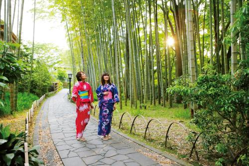 two women walking down a path in a bamboo forest at Sora Togetsusoukinryu in Izu