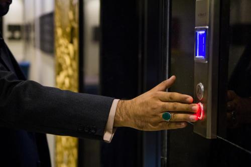 a hand presses a red button on an elevator at Luma Serviced Apartments in Al Madinah