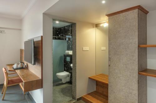 a bathroom with a toilet and a sink and a tv at Hotel Opal in Kolhapur