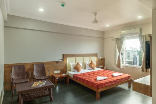 a bedroom with a bed and a table and a desk at Hotel Opal in Kolhapur