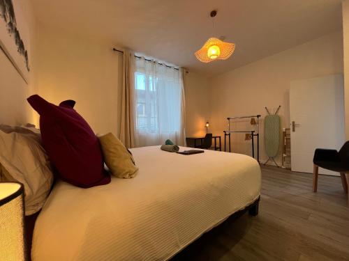 een slaapkamer met een bed met kussens en een raam bij La Suite D'Hélène - Appartement T2 50m2 entre Genève et Chamonix - Parking Privé in Scionzier