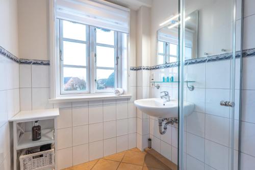 een witte badkamer met een wastafel en een douche bij Landhaus am Meer - Whg 7 Osterley in Utersum