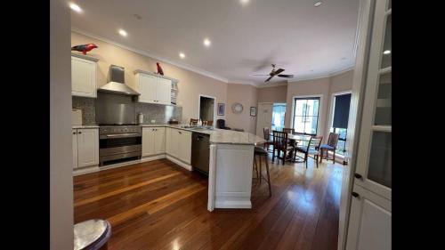 a kitchen with white cabinets and a wooden floor at Stately Bowral Designer Home in Bowral