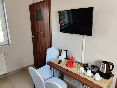 a room with a table with chairs and a television at Belweder in Białystok
