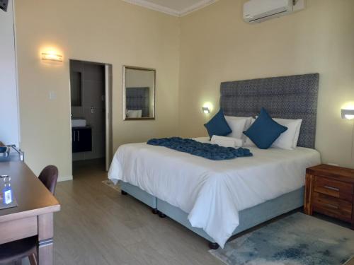 ein Schlafzimmer mit einem großen weißen Bett mit blauen Kissen in der Unterkunft Lucolo Palace B&B Queenstown in Queenstown
