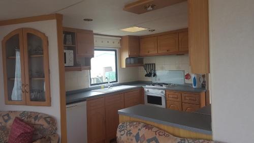 a kitchen with wooden cabinets and a counter top at The Chase Ingoldmells in Ingoldmells