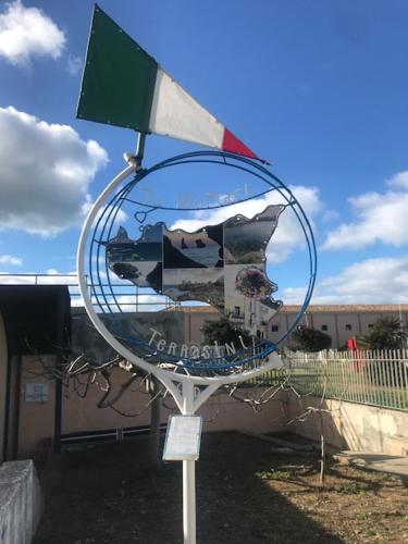 a large metal mirror with a flag on top of it at By the Sea in Terrasini