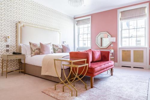 a bedroom with a bed and a chair and a mirror at The Queensberry Hotel in Bath