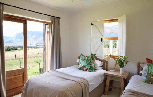 1 dormitorio con 2 camas y ventana con vistas a las montañas en BoPlaas Country Cottages, en Wellington