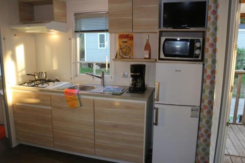 a kitchen with a white refrigerator and a microwave at Camping Parc Mogador in Sanary-sur-Mer