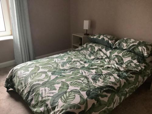 a bedroom with a bed with a green and white comforter at 4 Stills Apartment in Rothes