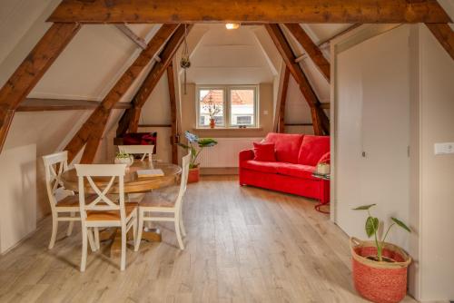 een woonkamer met een tafel en een rode bank bij Gunnery's Guest House in Alkmaar