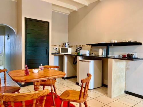 The Eden Lodge Boksburg في بوكسبرغ: مطبخ مع طاولة وكراسي خشبية في الغرفة