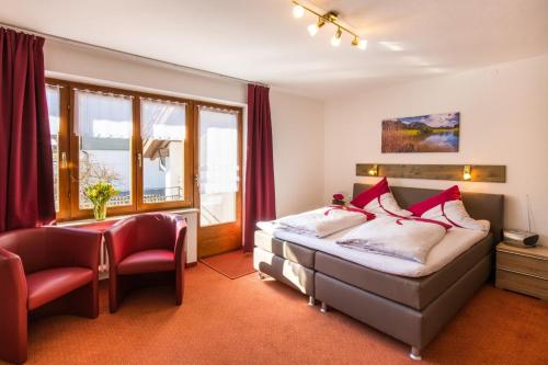 ein Schlafzimmer mit einem Bett, einem Stuhl und einem Fenster in der Unterkunft Gästehaus Wolfgang in Ruhpolding