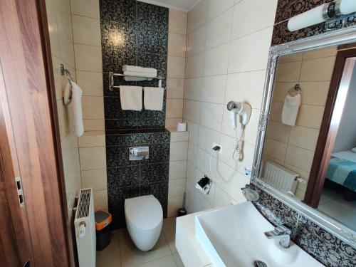 a bathroom with a toilet and a sink and a mirror at Belweder in Białystok