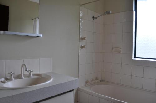 y baño blanco con lavabo y bañera. en Karri Valley Chalets, en Pemberton
