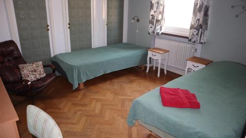 a room with two beds and a chair and a window at Kronans B&B in Hässleholm