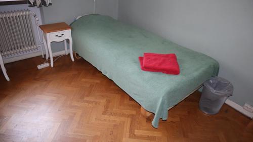 Una cama con una manta verde y una almohada roja. en Kronans B&B, en Hässleholm