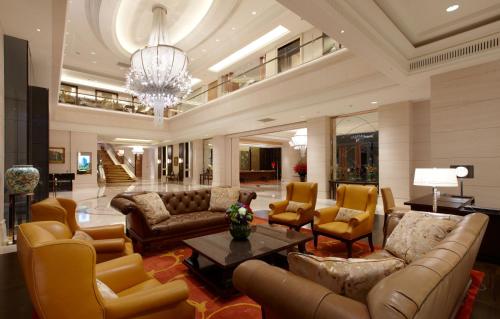 Un vestíbulo con sofás y sillas y una lámpara de araña. en The Okura Prestige Taipei, en Taipéi
