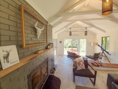 a living room with a fireplace and a brick wall at RIVERLEA RETREAT MUDGEE - Private, Outdoor Bath, Pool, Tranquility in Apple Tree Flat