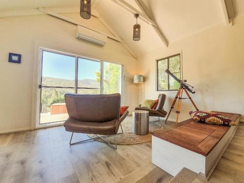 a living room with a chair and a table at RIVERLEA RETREAT MUDGEE - Private, Outdoor Bath, Pool, Tranquility in Apple Tree Flat