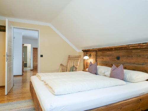a bedroom with a large white bed with a wooden headboard at Landgasthof & Restaurant Batzenhäusl in Sankt Gilgen