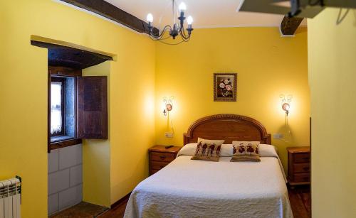 a bedroom with yellow walls and a bed with white sheets at La Corrolada in Avín