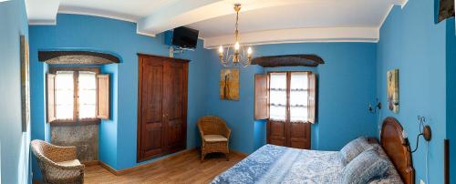 a blue bedroom with a bed and two windows at La Corrolada in Avín