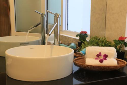 a bathroom counter with a sink and a bowl with towels at Ylang Garden Villa in Hoi An