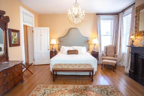 ein Schlafzimmer mit einem Bett, einem Kamin und einem Kronleuchter in der Unterkunft Kehoe House, Historic Inns of Savannah Collection in Savannah