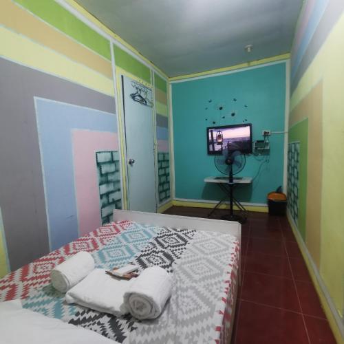 a bedroom with a bed with towels and a television at Cabanatuan City PNY TRANSIENT INN 3 in Cabanatuan