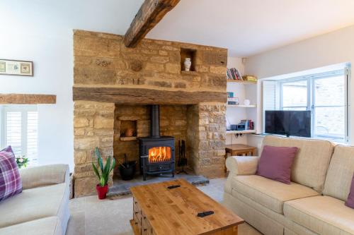 a living room with a stone fireplace and a couch at Crofter's Barn in Chipping Norton
