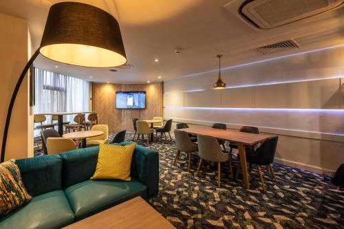 a waiting room with a couch and tables and chairs at Holiday Inn London - Regent's Park by IHG in London